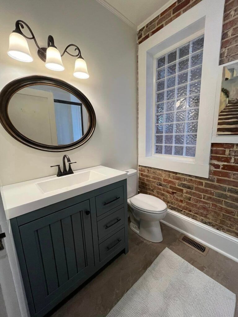 One brick wall with white wall behind updated bathroom sink