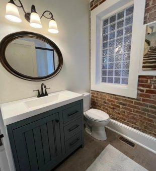 One brick wall with white wall behind updated bathroom sink